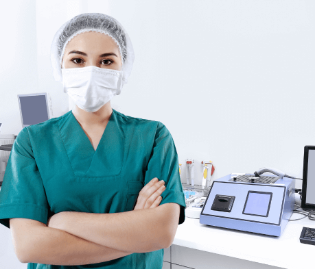 Imagen de una persona de laboratorio mirando fijamente a la cámara y de fondo se puede observar los equipos de laboratorio.